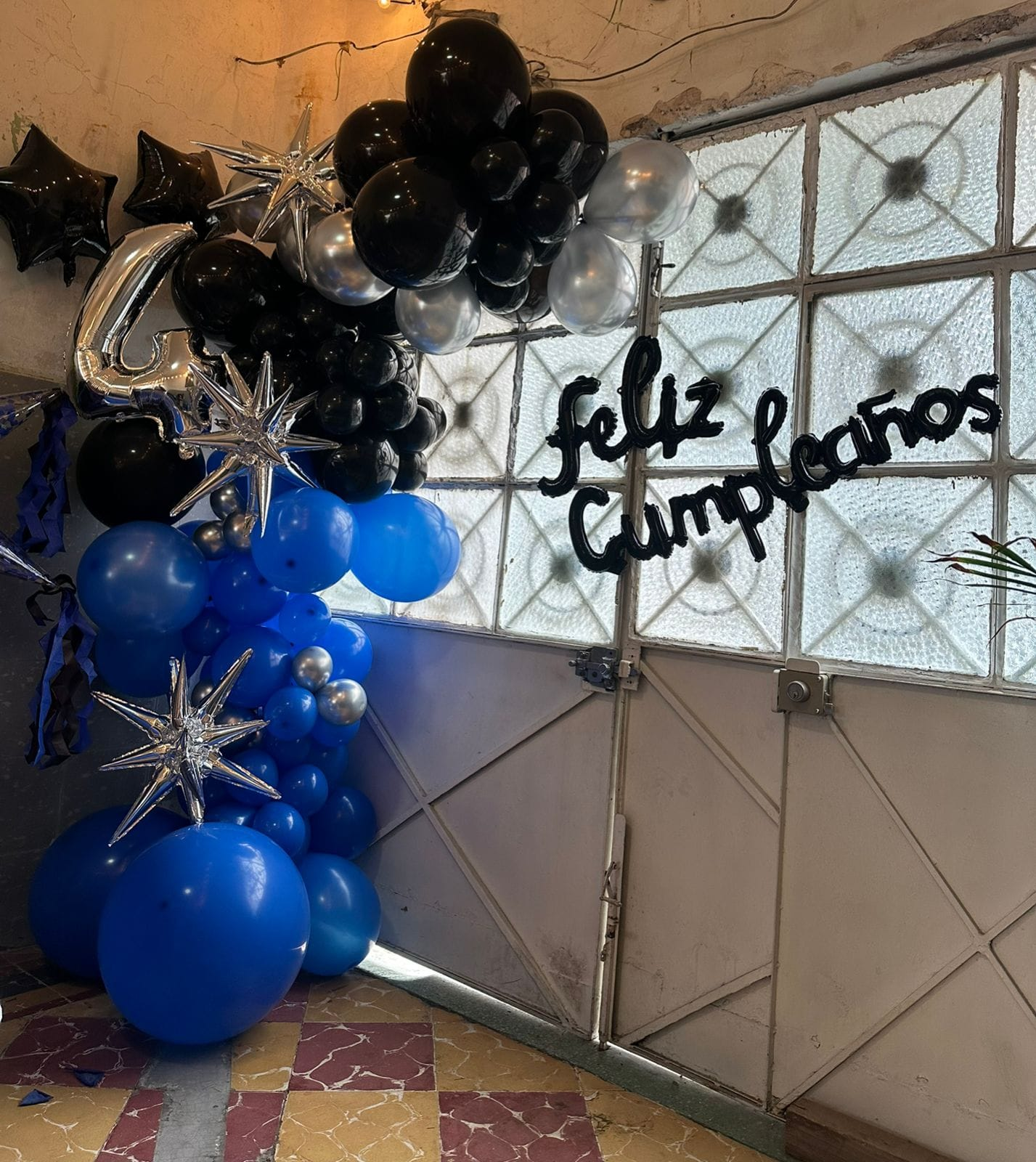 Decoración de cumpleaños con globos azules, negros y plateados realizada en México