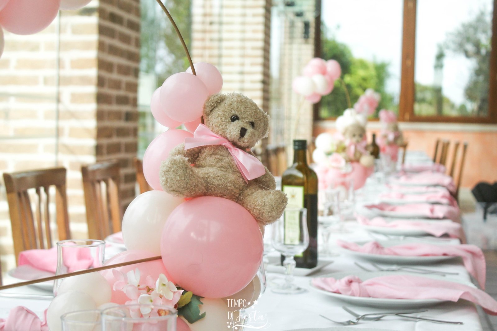 Composición de mesa con globos rosas y osito